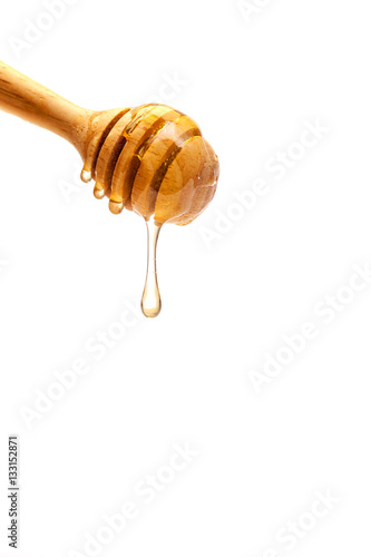 Drop of brown honey on a wooden spoon.