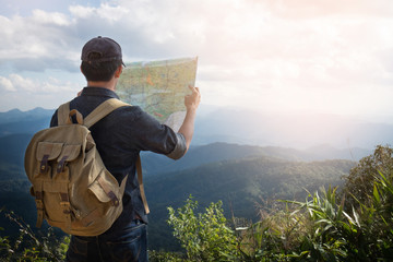 Young Man Traveler with map backpack relaxing outdoor with rocky