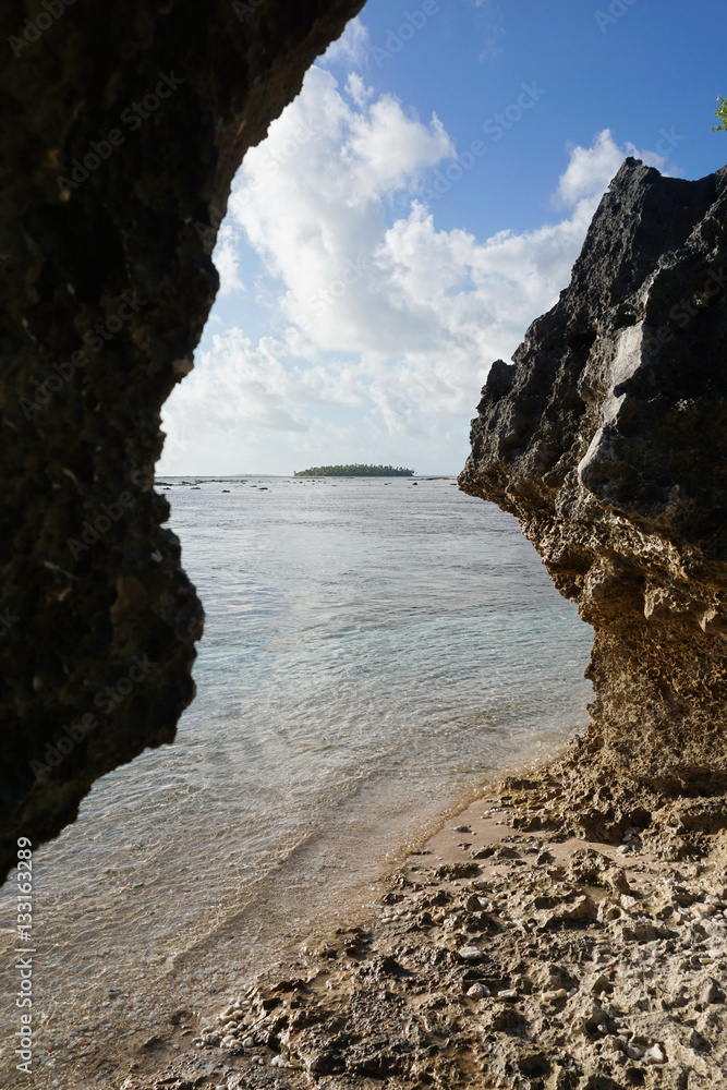 An islet in background between eroded rocks on the sea shore, atoll of Tikehau, Tuamotu archipelago, French Polynesia, south Pacific ocean
