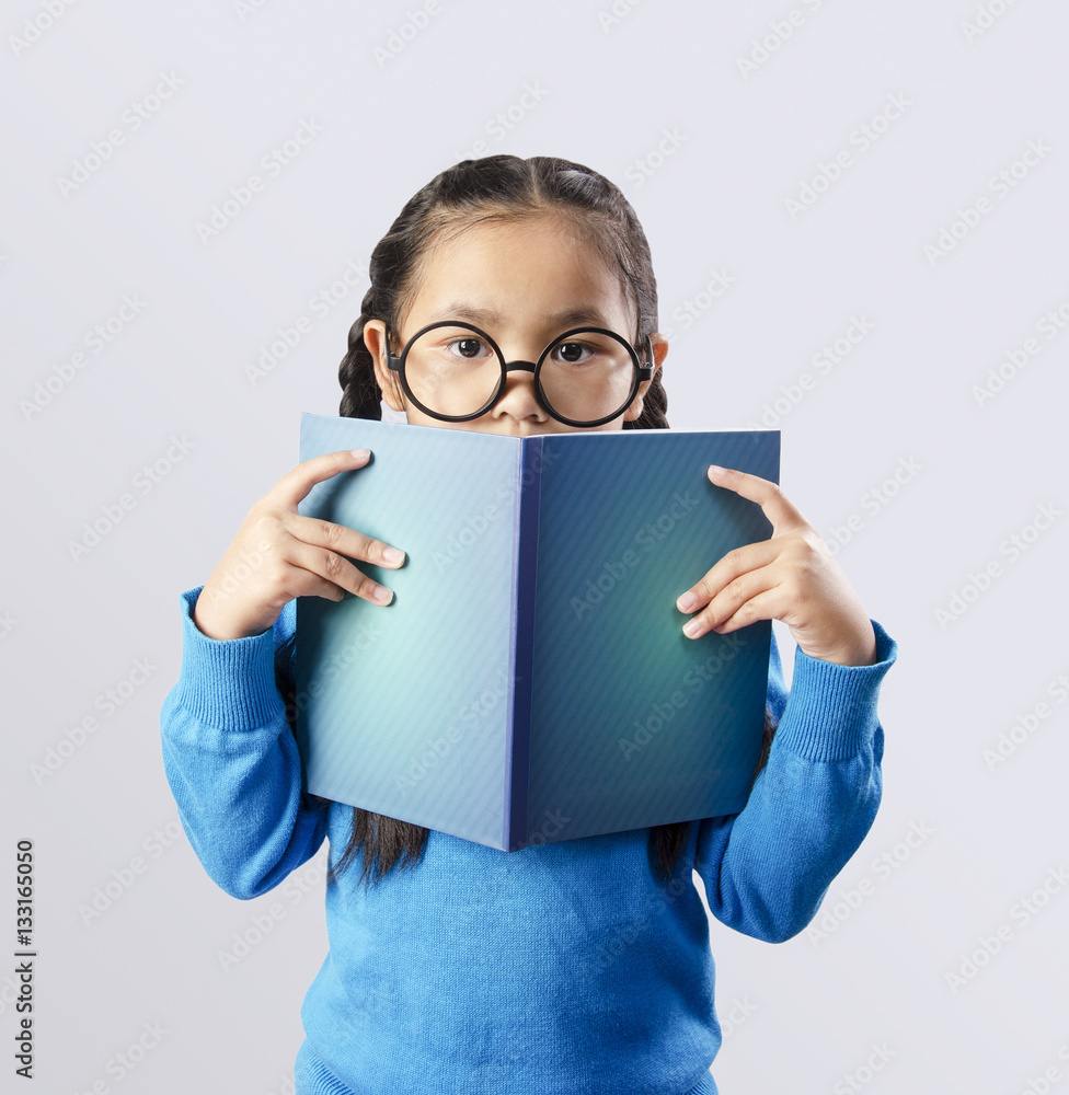 Education concept of asian little girl wearing big glasses while holding a open book Education concept of asian little girl wearing big glasses while holding a open book