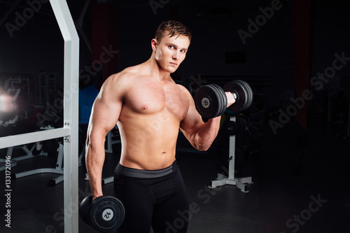 Closeup portrait of professional bodybuilder Strong muscular yang man doing exercise. Workout with barbell at gym. Sports and fitness. Training guy pumping up hands biceps. 