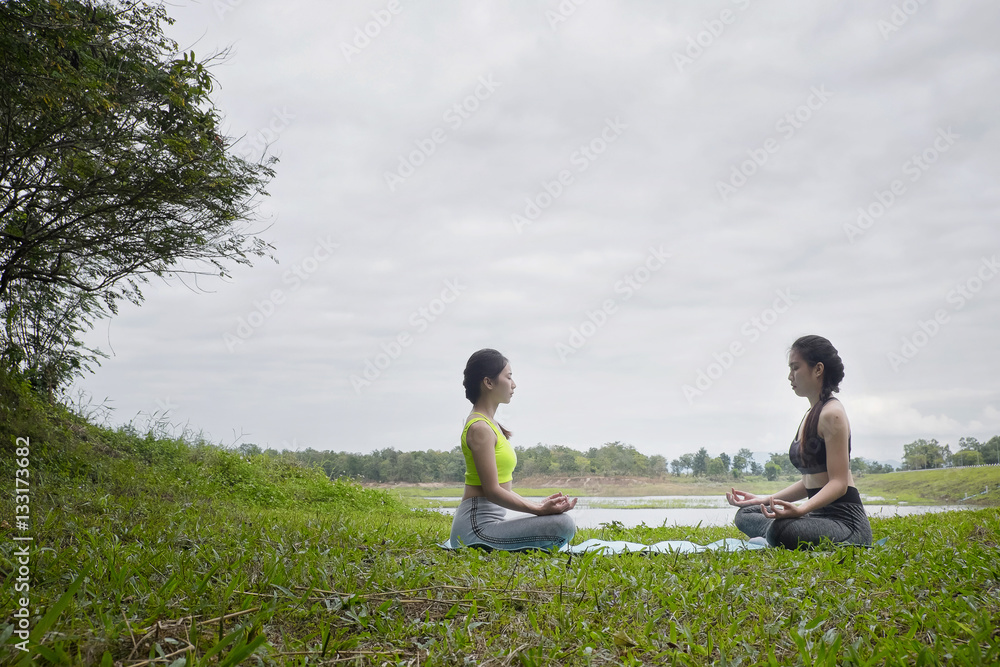 Two young girl doing yoga fitness exercise outdoor in beautiful