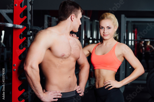 Muscular couple discussing together with arm on shoulder