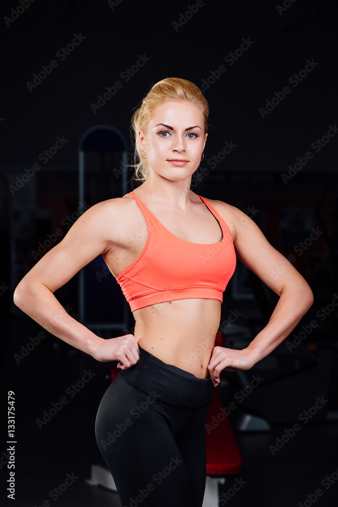 Portrait of smiling sporty woman standing. Posing on a dark background Portrait of smiling sporty woman standing. Posing on a dark background