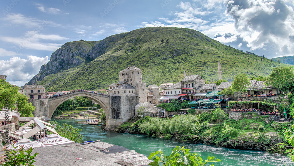 Fototapeta premium Mostar, Bosnia Herzegovina - May 1, 2014: Stari Most bridge and the cross on the hill in Mostar