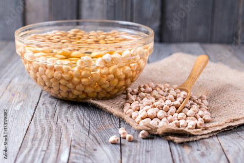 Obraz na plátně Uncooked chickpeas in wooden spoon on wooden background