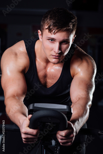 Portrait of a handsome man workout on  fitness  the exercise bike   dark at gym. © photominus21