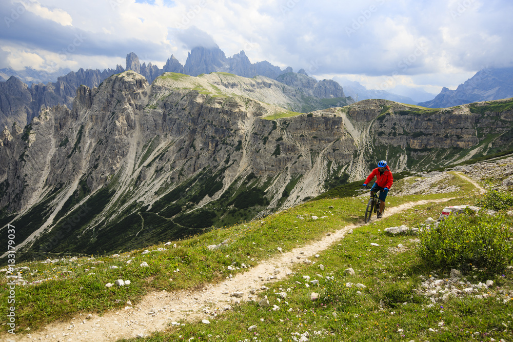 View of cyclist riding mountain bike on trail in Dolomites,Tre C