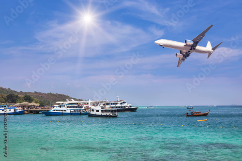  passenger airplane landing above tropical sea with cruising ships and boats moored in bay. travel destinations concept.