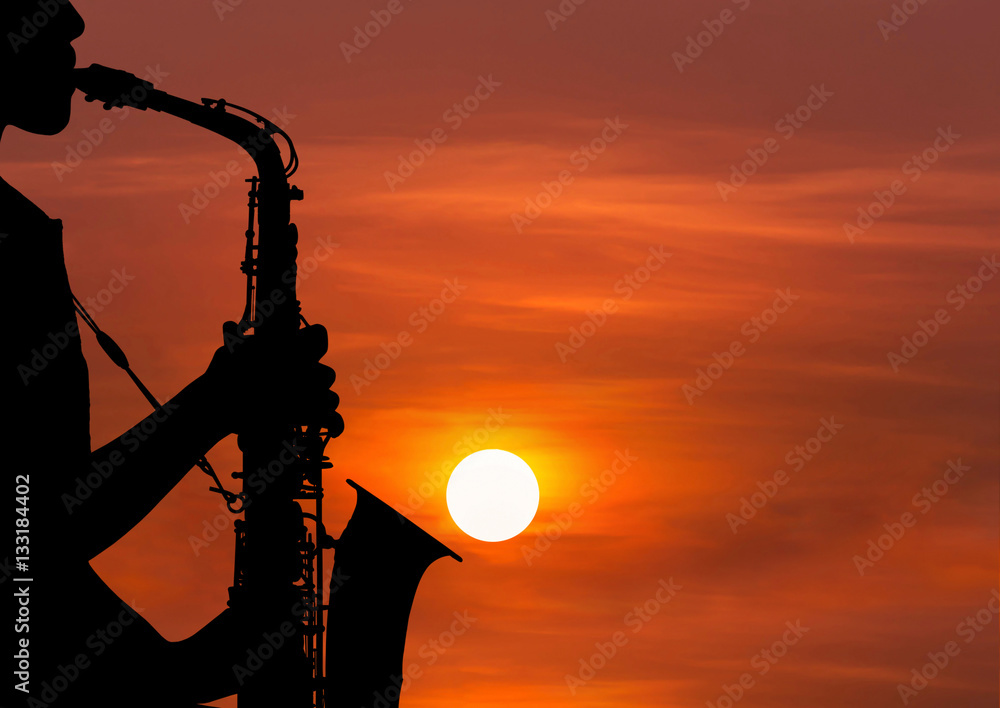 Obraz premium silhouette young woman playing the saxophone in sunset
