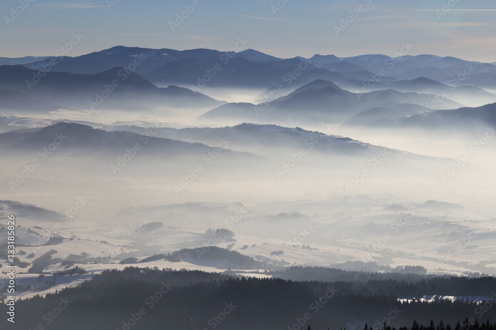 Winter mountain landscape -  view of  snow, mist covered valley.