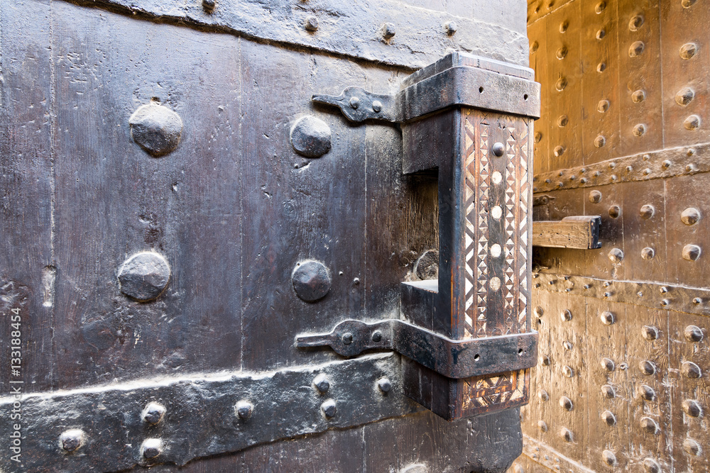 Wooden old latch of the wooden ancient gate of the caravansary (Wikala) of Bazaraa, Cairo, Egypt Wooden old latch of the wooden ancient gate of the caravansary (Wikala) of Bazaraa, Cairo, Egypt