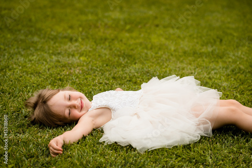 Little girl lying on grass lawn smiling photo