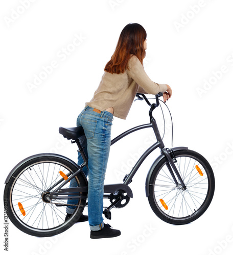 back view of a woman with a bicycle. cyclist sits on the bike. 