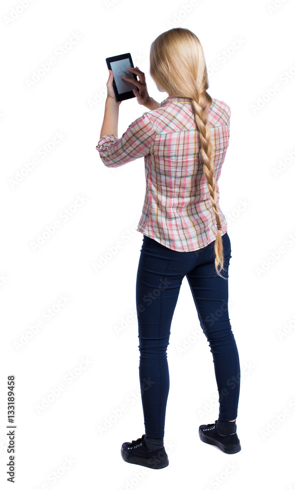 back view of standing young beautiful girl with tablet computer in the hands of. girl watching. Rear view people collection. backside view of person. Isolated over white background. back view of standing young beautiful girl with tablet computer in the hands of. girl watching. Rear view people collection. backside view of person. Isolated over white background.