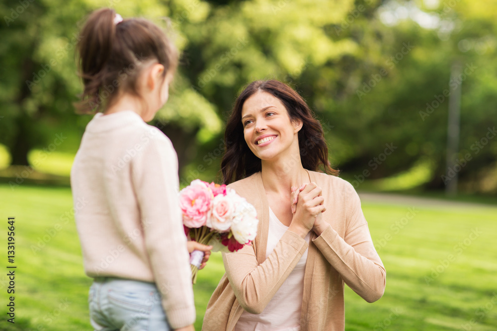 Naklejka premium girl giving with flowers to mother in summer park