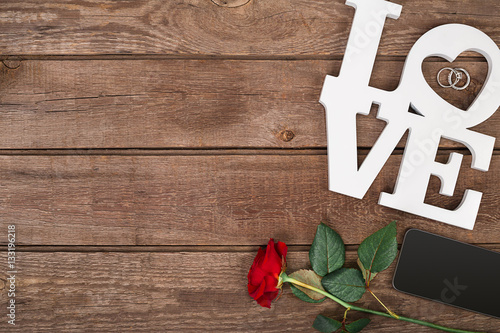 Red rose and smart over wooden background