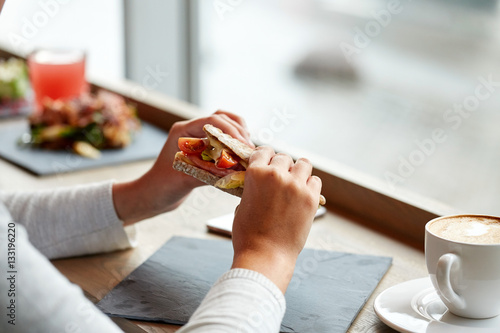 woman eating salmon panini sandwich at restaurant