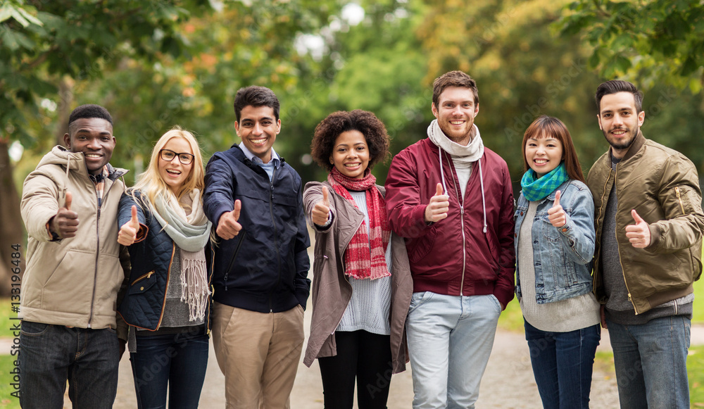 happy friends showing thumbs up at autumn park