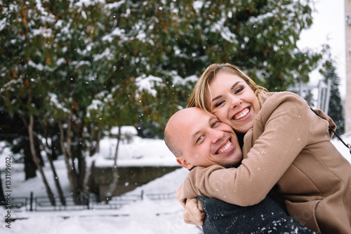 Couple smiling with perfect teeth hugging and looking at camera in winter 