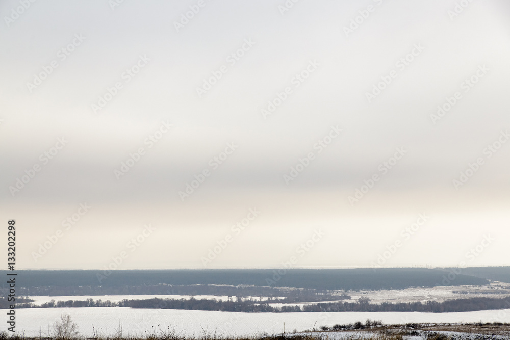 The gloomy winter sky over the snowy field.