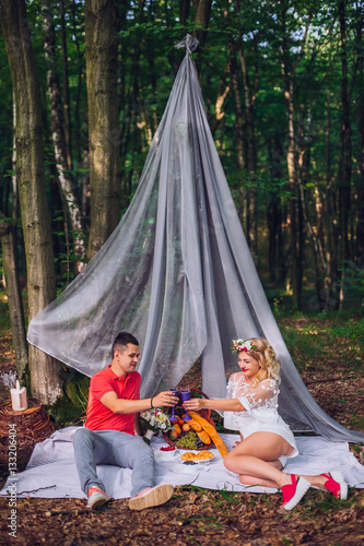 Young enamoured couple on picnic in wood. Funny moment. Eating grape. Lovely together. © nataliakabliuk