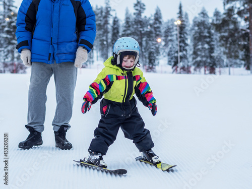 Child learn skiing in the mountains. Toddler kid in helmet learn