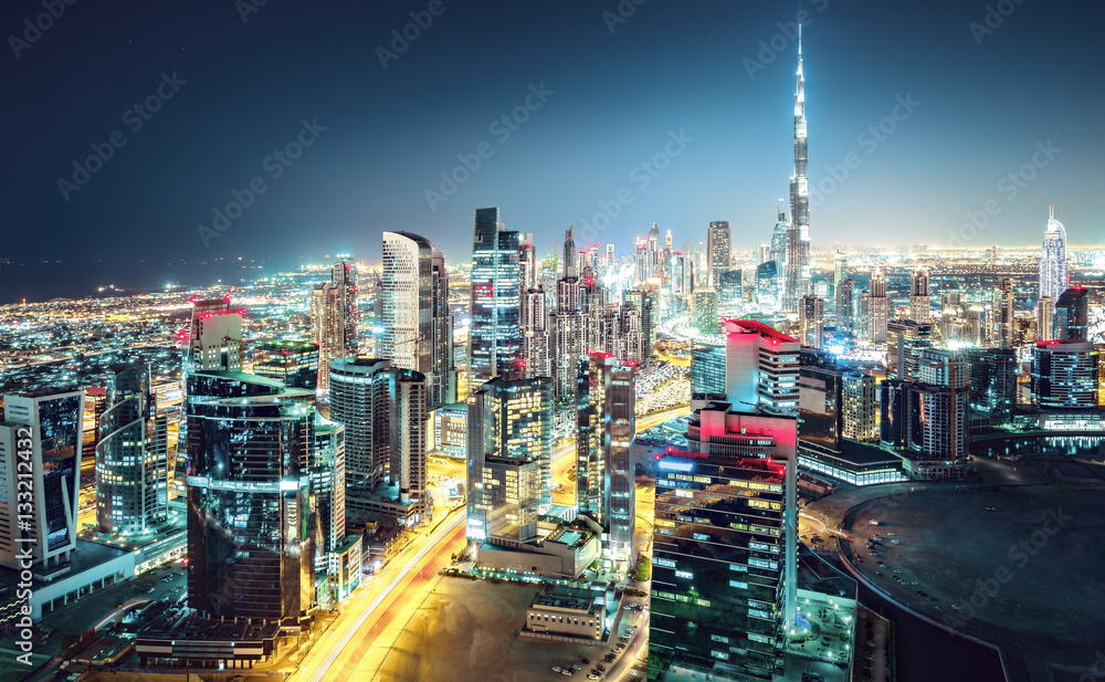 Fototapeta premium Niesamowita nocna panorama: drapacze chmur dużego, nowoczesnego miasta. Śródmieście, Dubaj, Zjednoczone Emiraty Arabskie. Kolorowy pejzaż.