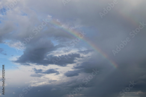 Rainbow in the gray white clouds against the blue sky, close-up © v_ridjin