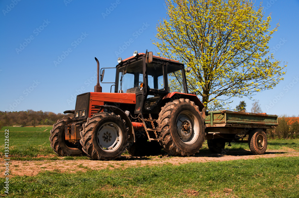 Old rusty tractor with a trolley on a spring field in Germany Old rusty tractor with a trolley on a spring field in Germany