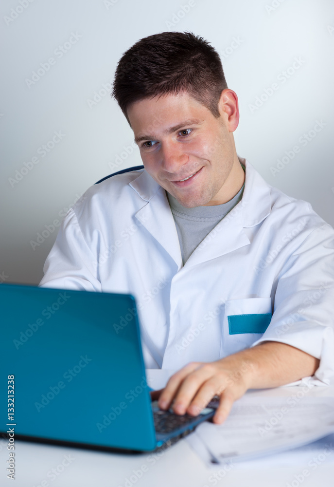 Young scientist with computer reading content with a smile on his face Young scientist with computer reading content with a smile on his face
