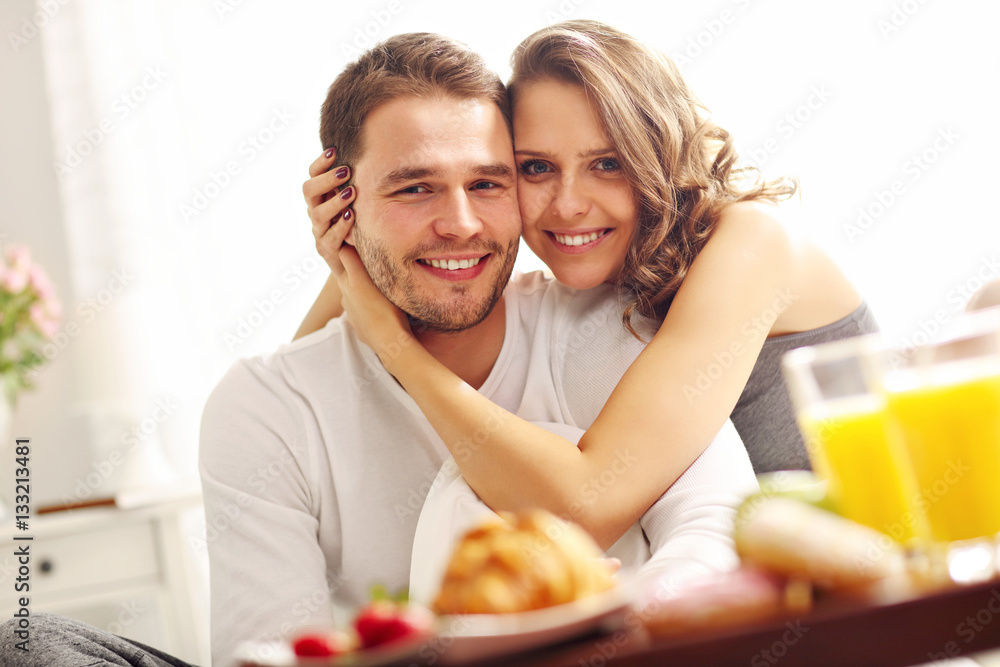 Young couple eating breakfast in bed