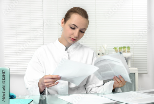 Young attractive female scientist or graduate student reads scie