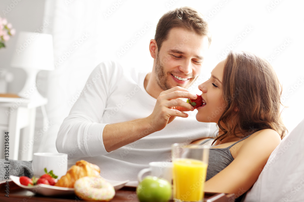 Young couple eating breakfast in bed