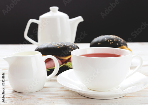 Black Hamburger , cup of tea and milk for breakfast.