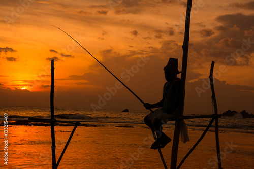 Fotografia, Obraz Silhouettes of the traditional Sri Lankan stilt fishermen at the sunset in Weligama, Sri Lanka