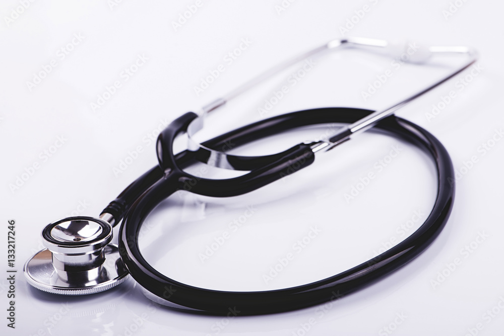 Folded metal stethoscope with black tube lying on white surface. Horizontal studio shot. Folded metal stethoscope with black tube lying on white surface. Horizontal studio shot.