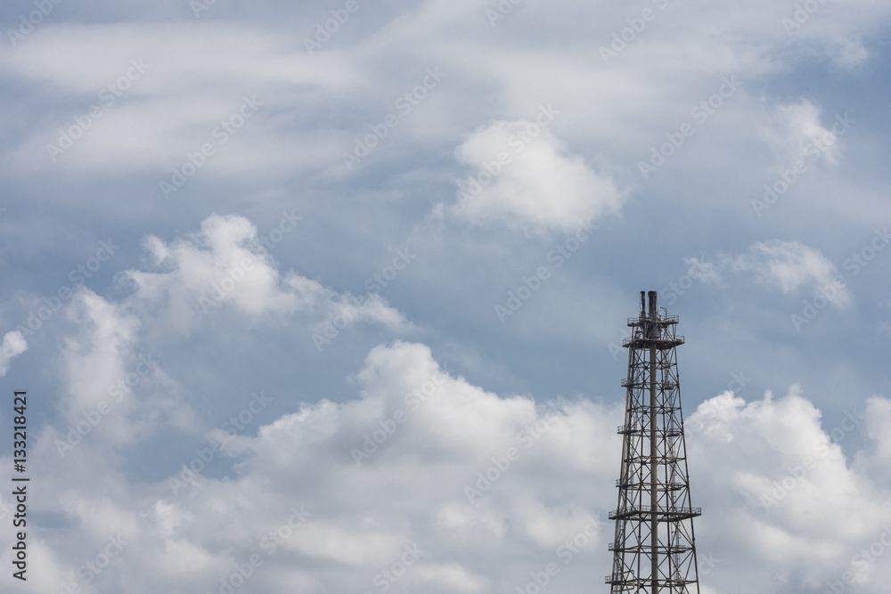 oil refinery - flare tower with a cloudy blue sky background