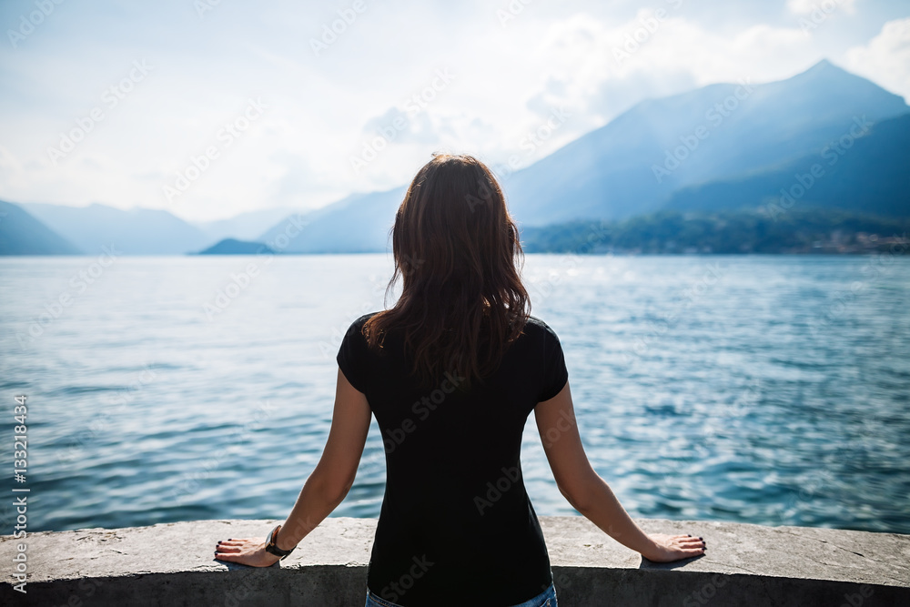 Fototapeta premium Back view of young woman relaxing on terrace on lake Como, Italy