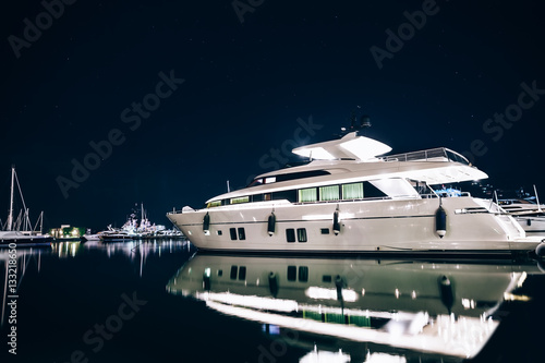 Luxury yachts in La Spezia harbor at night with reflection in wa