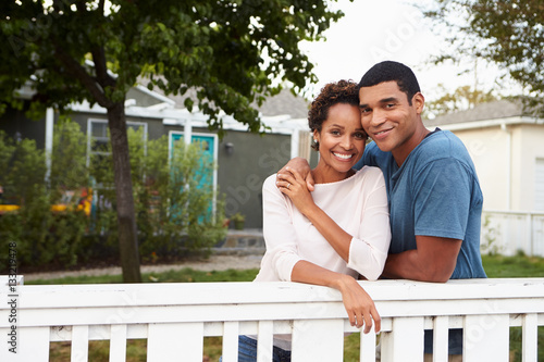 Young African American couple embrace outside their house