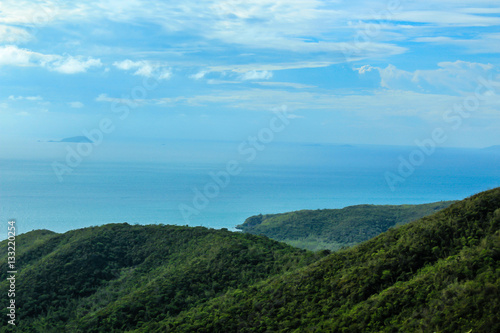 Scenic landscape of ocean at sunny day and beautiful blue sky from tropical island with mountains overgrown dense green jungle tree.