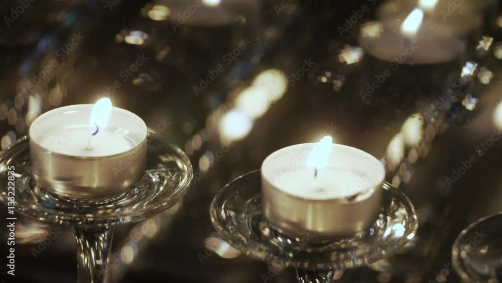 Small candles are displayed in a window. Reflection of candles in a window. The flame of a candle waves on wind. Many small candles cost on a window sill. Holiday divali. Divali Small candles are displayed in a window. Reflection of candles in a window. The flame of a candle waves on wind. Many small candles cost on a window sill. Holiday divali. Divali