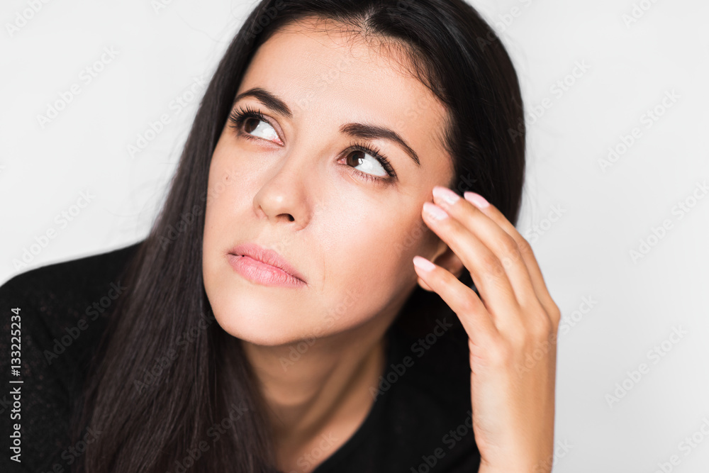 Close up portrait of brunette pretty woman with headache touching her face, look up. Beautiful woman stressed and worry in black sweater on light grey background. Healthcare and medicine. Close up portrait of brunette pretty woman with headache touching her face, look up. Beautiful woman stressed and worry in black sweater on light grey background. Healthcare and medicine.