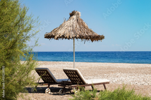 Sunshades and chaise lounges on beach. Summer seascape.