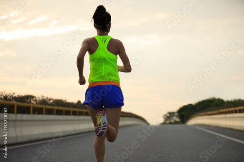 young fitness asian woman runner running on city road