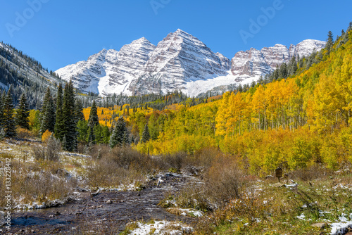 Autumn at Maroon Bells - An autumn morning, after some overnight snowfall, Maroon Creek, with freshly melted water, running down from the side of famous Maroon Bells mountains, Aspen, Colorado, USA.