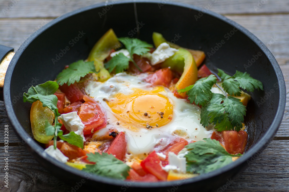 fried egg in a pan with tomatoes and greens fried egg in a pan with tomatoes and greens
