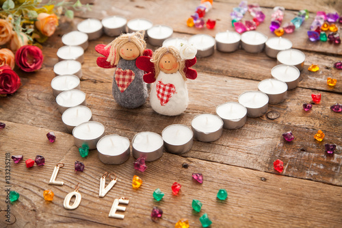 Valentine's day angels in made of candles heart with letters signed by colorful stones. Word Love signed with letters and toy couples.