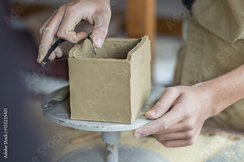 Young male potter master hands working with clay in pottery work